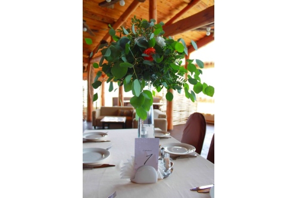 Оформление гостевых столов композициями из декоративной бутонов и живой зелени на высокой вазе