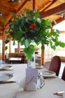 Оформление гостевых столов композициями из декоративной бутонов и живой зелени на высокой вазе